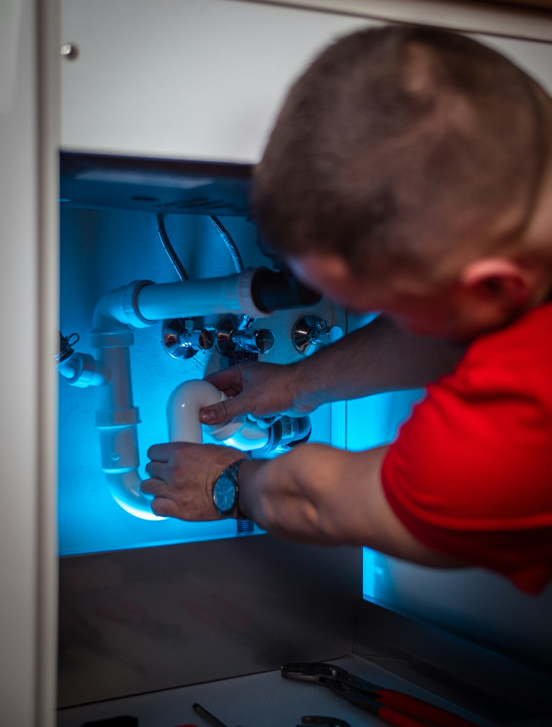a-man-working-on-a-pipe-in-a-cabinet-wzijll4kb-4